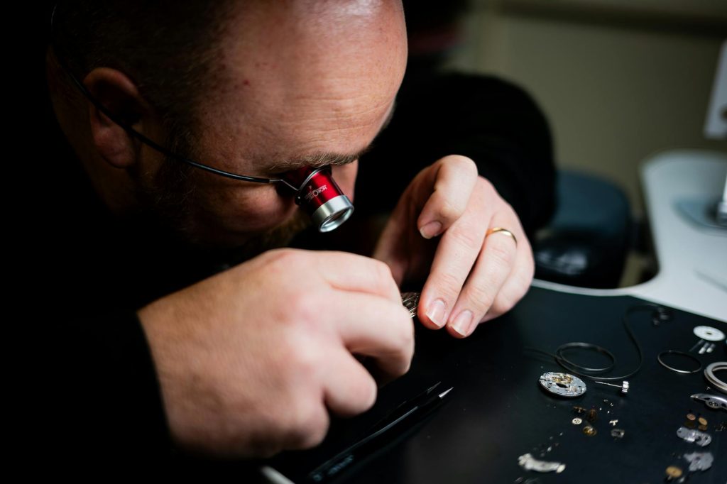 A skilled watchmaker carefully repairing a luxury timepiece at a professional workbench surrounded by precision tools